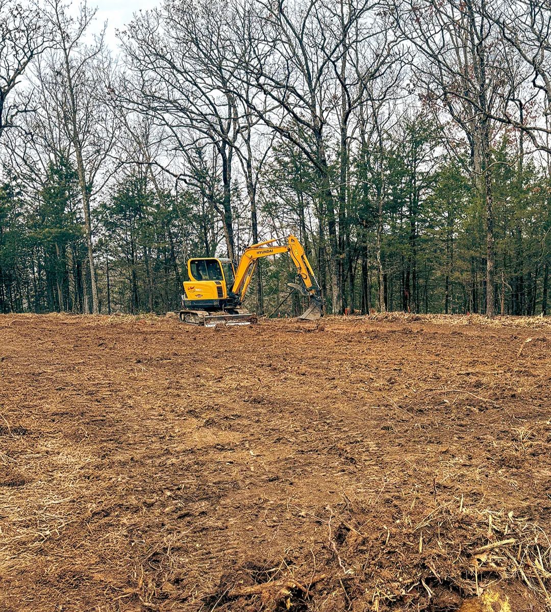 Excavator clearing trees for new construction site in Bentonville, AR