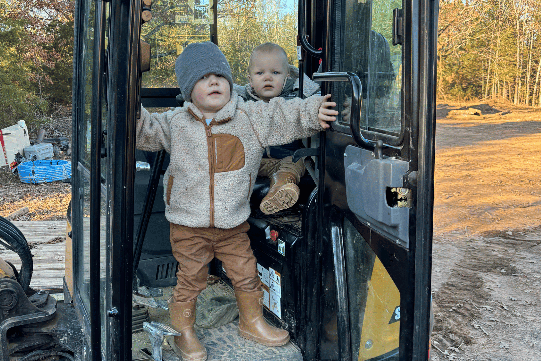 Two children sitting inside the cabin of an excavator